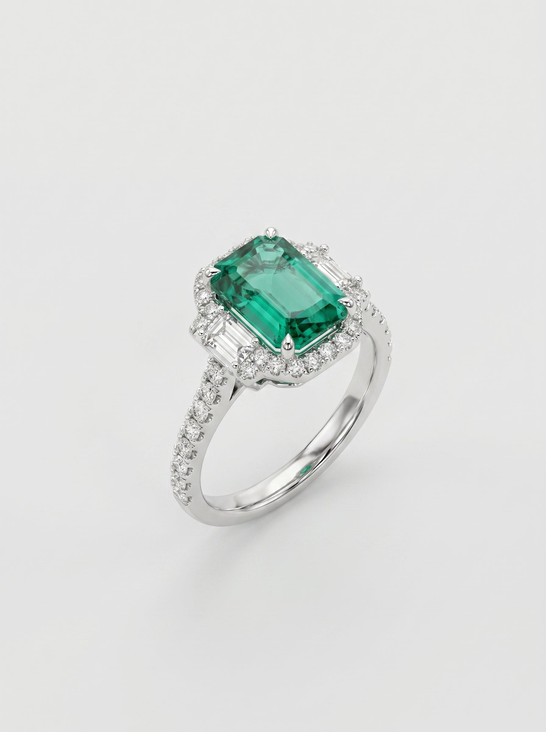 Ring with a green emerald gemstone and diamond-studded band on a light gray background