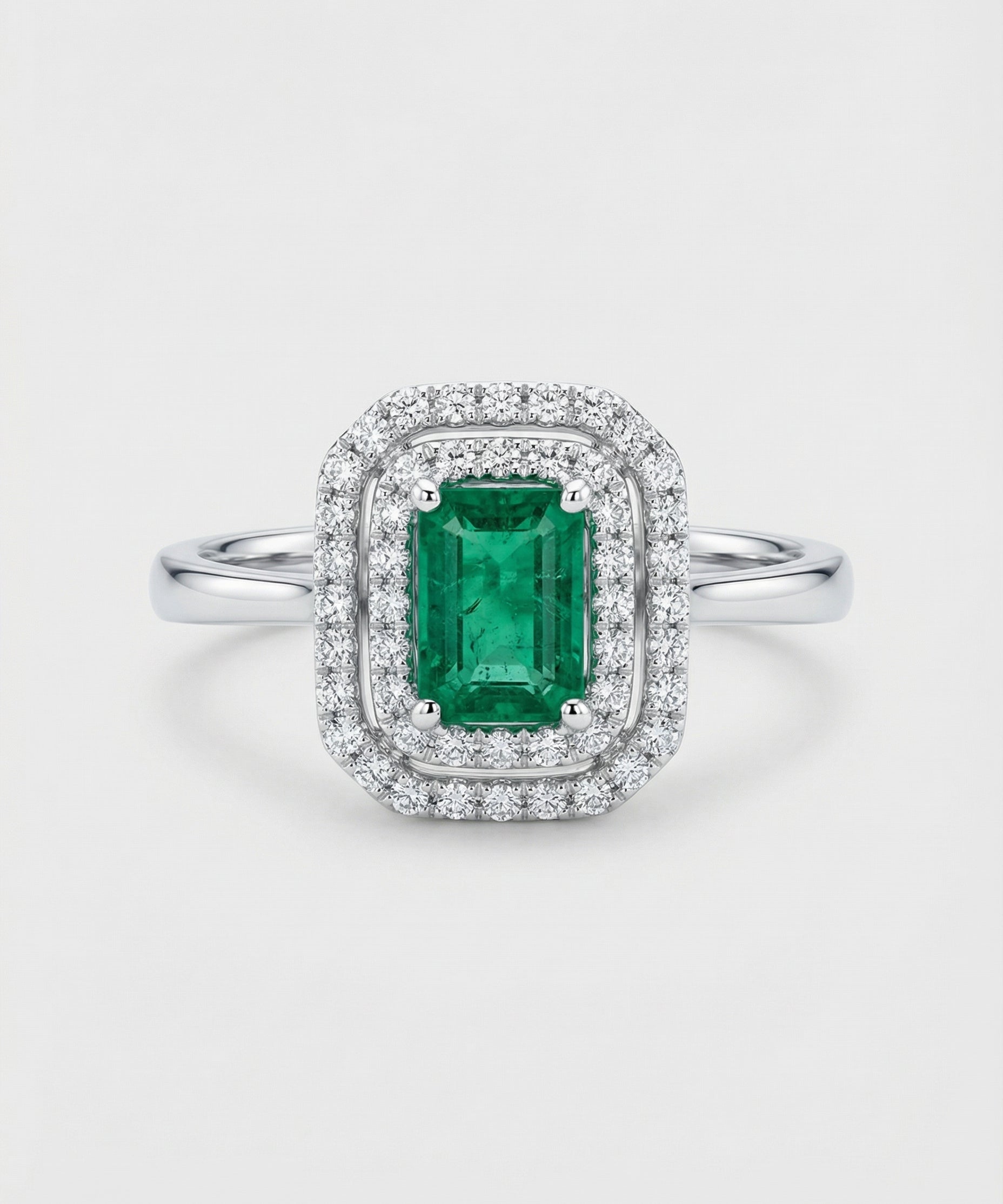 Ring with a green emerald gemstone and diamond accents on a white background