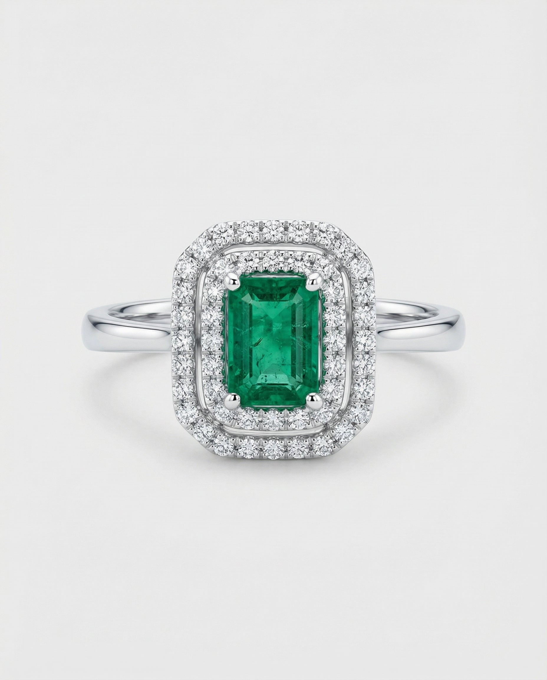 Ring with a green emerald gemstone and diamond accents on a white background