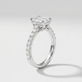 Diamond ring with a central emerald-cut diamond and smaller diamonds on a light gray background