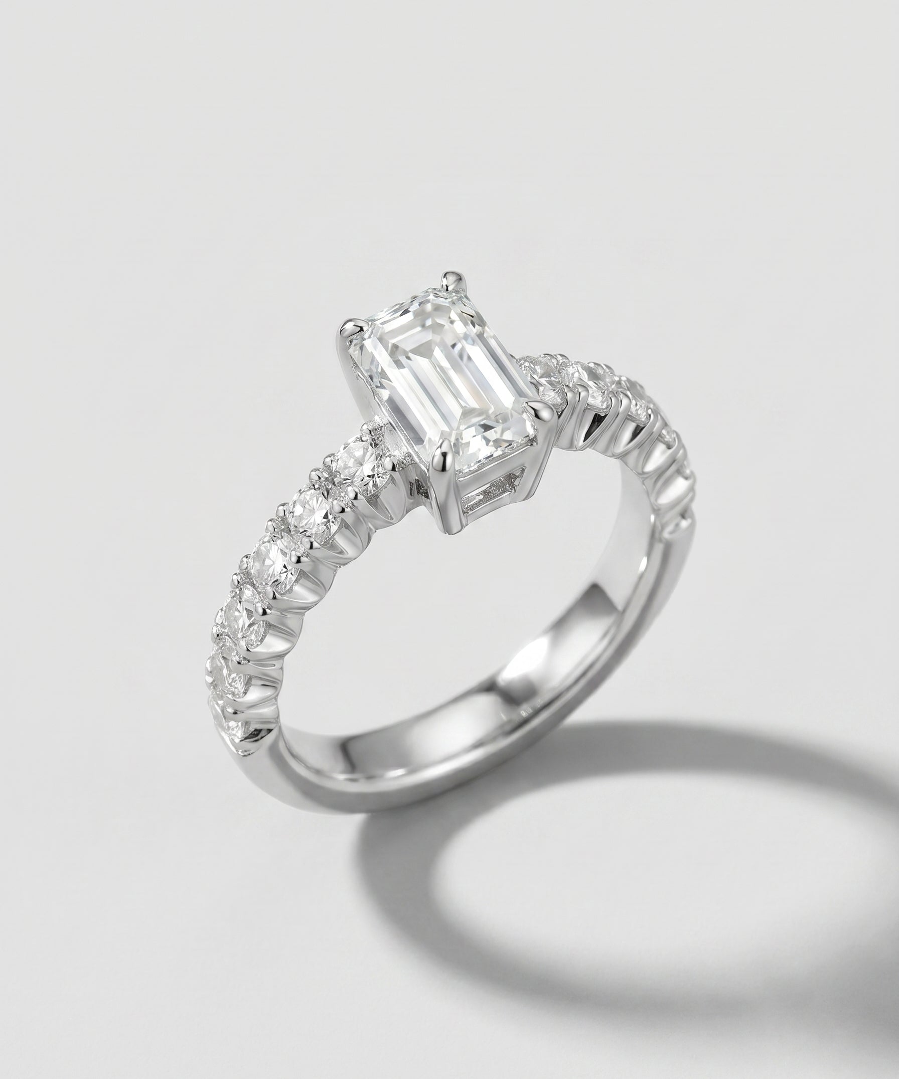 Engagement ring with an emerald-cut center diamond and pave diamond shanks
