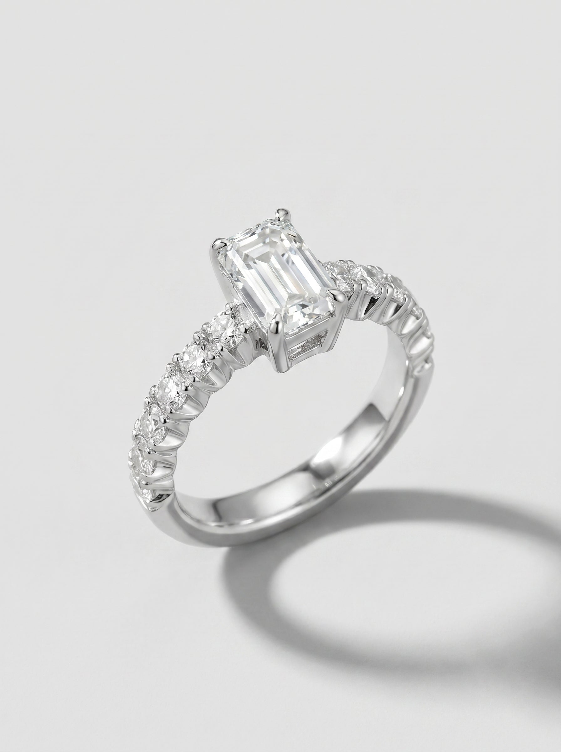 Engagement ring with an emerald-cut center diamond and pave diamond shanks