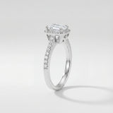 Emerald-cut halo engagement ring with a diamond on a light gray background