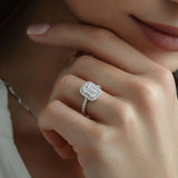 Close-up of a hand wearing an emerald-cut diamond ring with a soft focus background