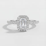 Diamond ring with emerald-cut center stone on a light gray background