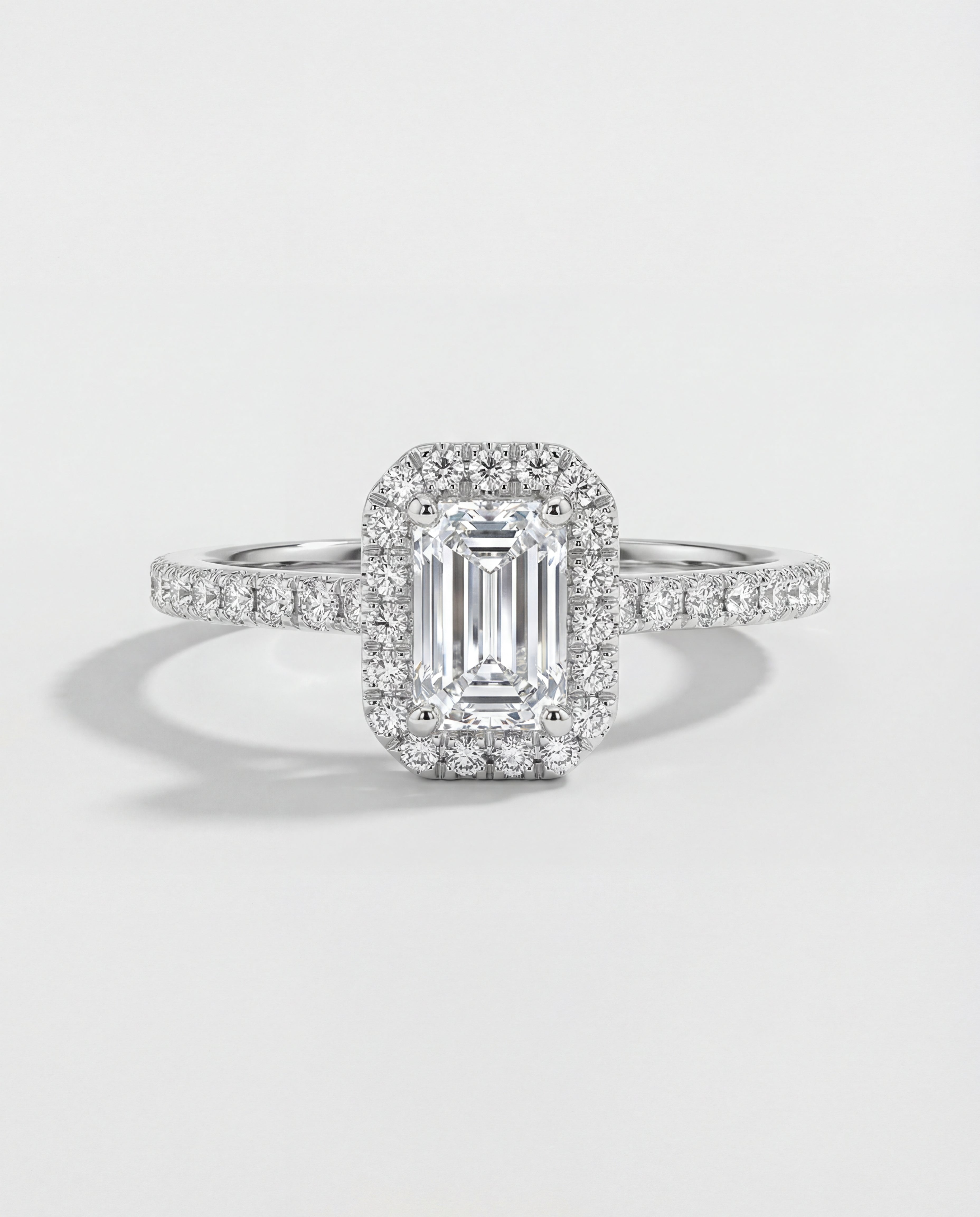 Diamond ring with emerald-cut center stone on a light gray background