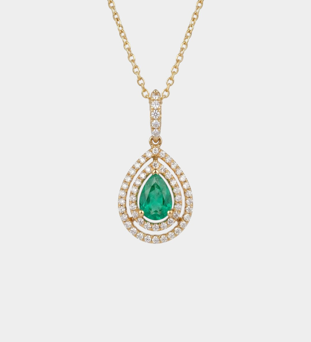Gold necklace with a green emerald gemstone pendant on a white background