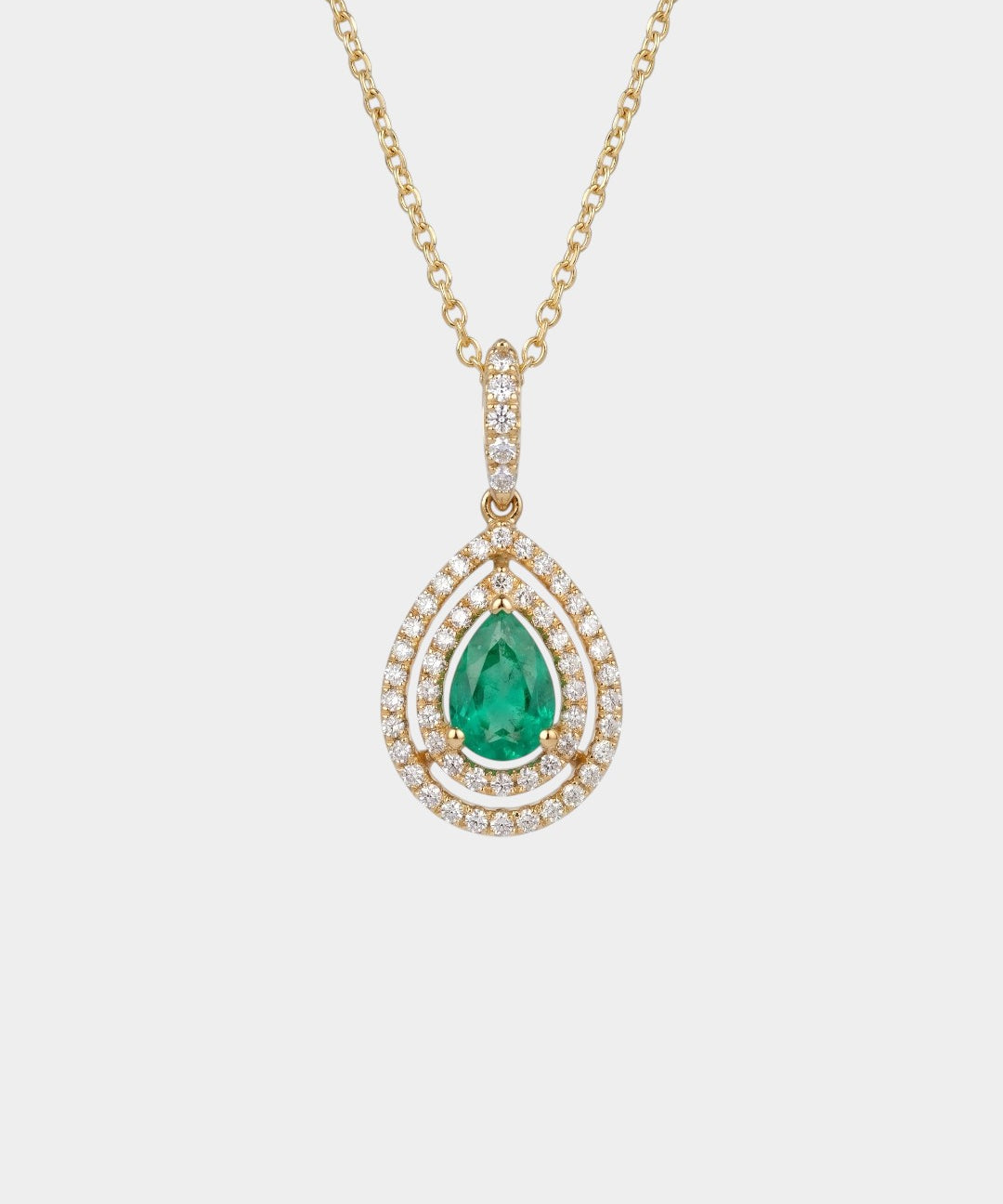 Gold necklace with a green emerald gemstone pendant on a white background