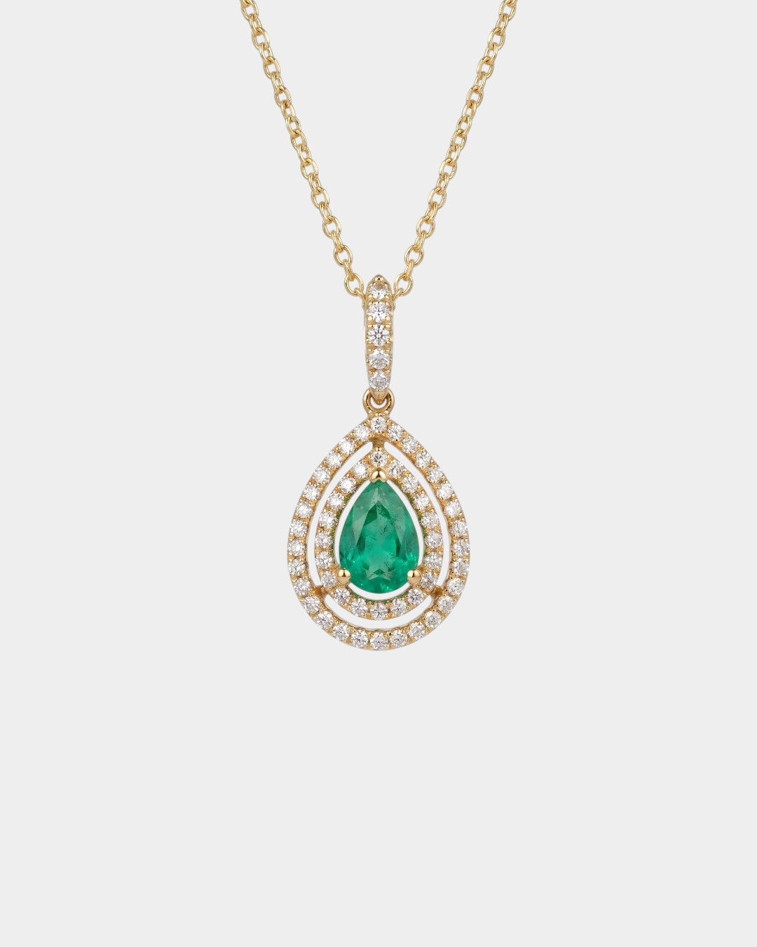 Gold necklace with a green emerald gemstone pendant on a white background