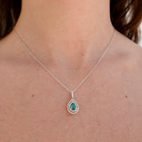 Necklace with a pendant featuring a green emerald gemstone on a person's neck.