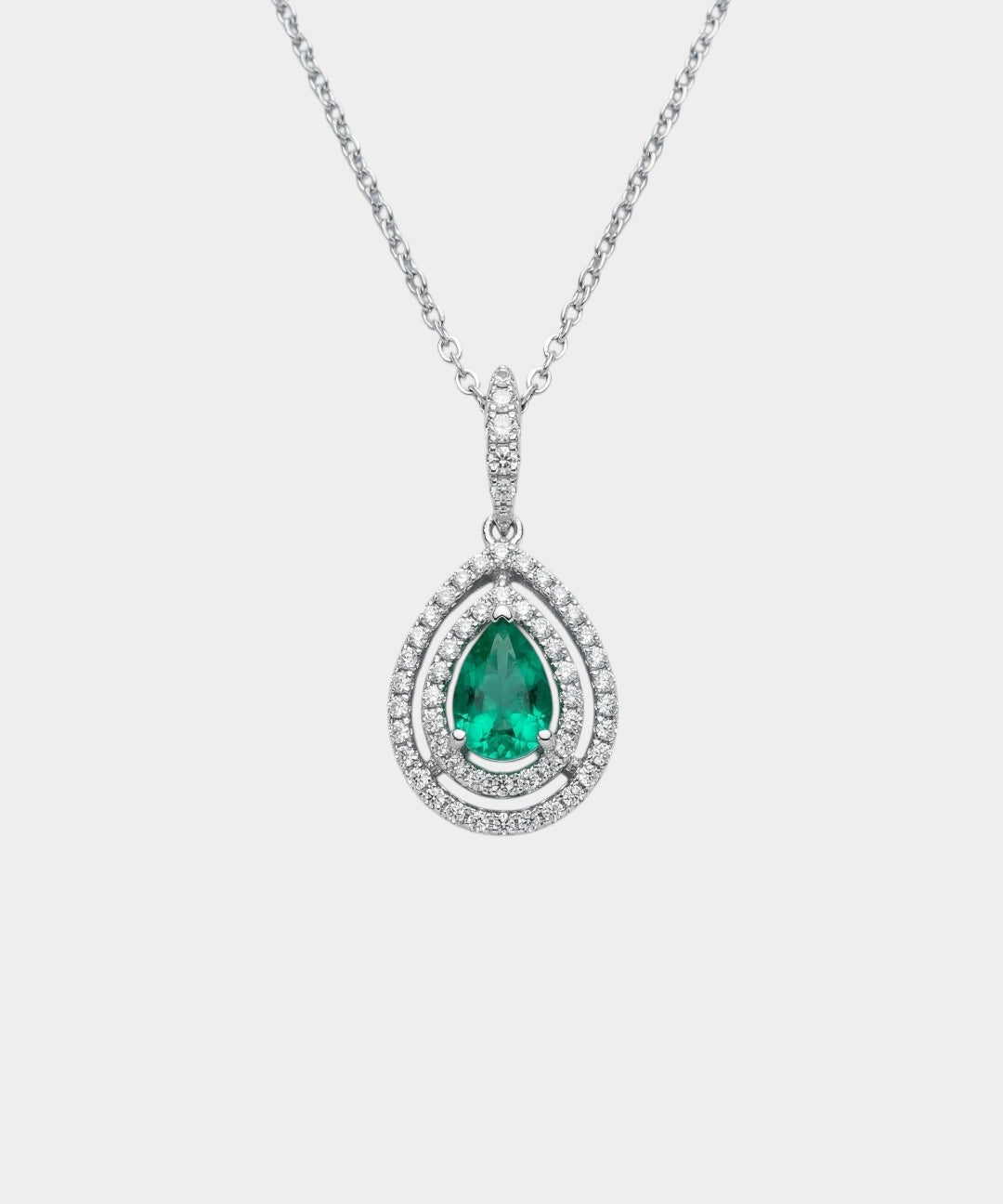Teardrop-shaped emerald pendant with diamond accents on a white background