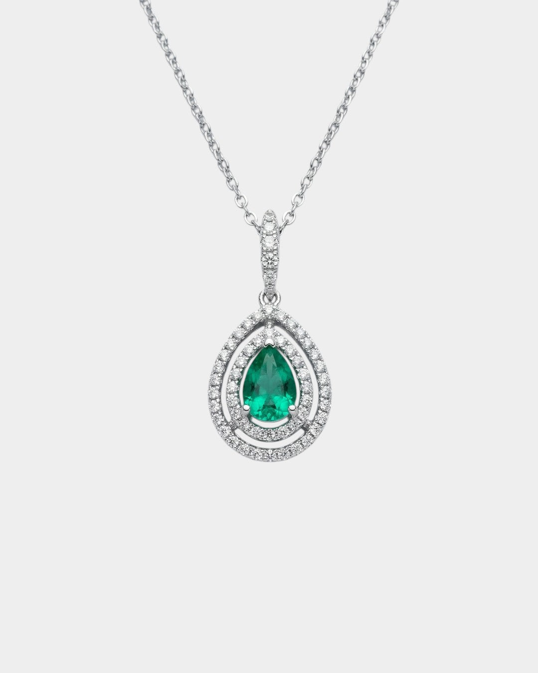 Teardrop-shaped emerald pendant with diamond accents on a white background