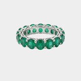 white gold ring with green emerald gemstones on a light gray background