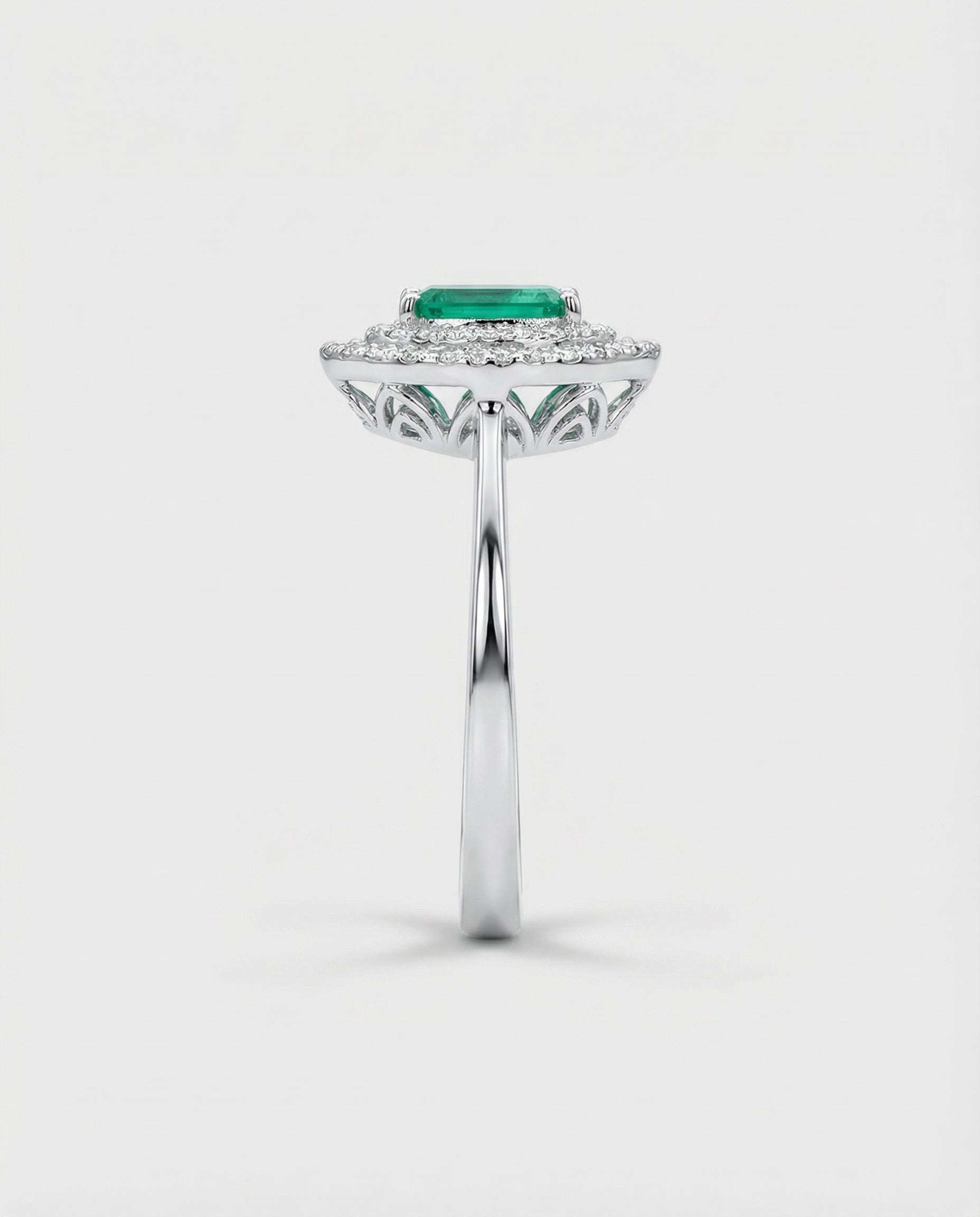 White gold ring with a green emerald gemstone on a white background
