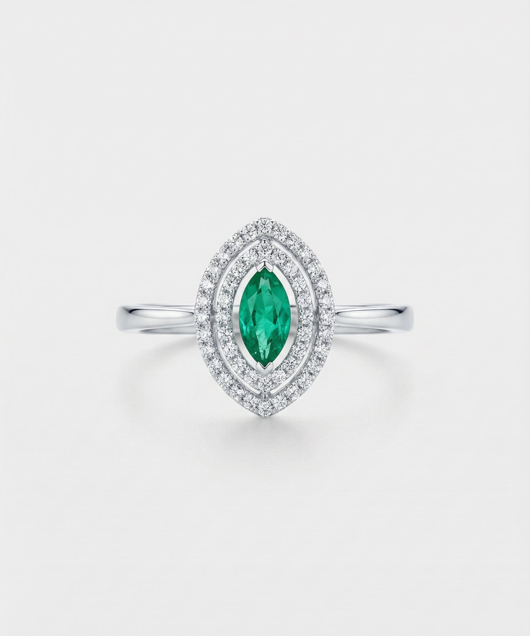 Ring with a green emerald gemstone and diamond accents on a light gray background