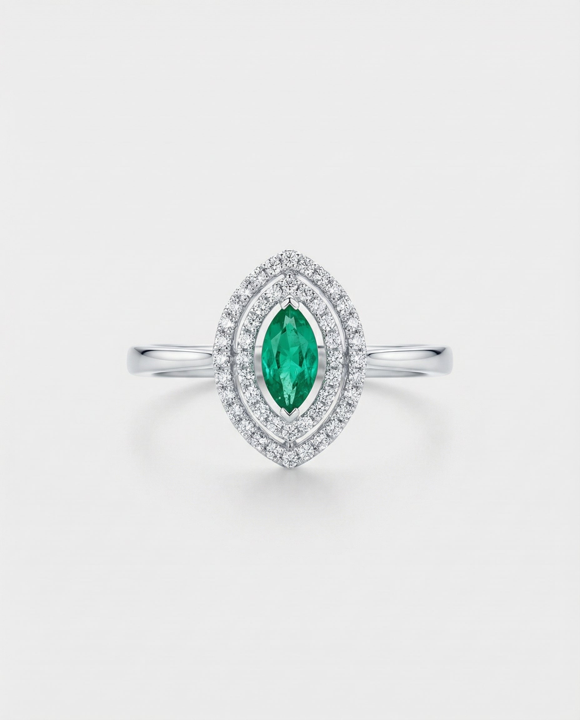 Ring with a green emerald gemstone and diamond accents on a light gray background