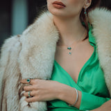 Woman wearing a green dress with a fur coat and jewelry