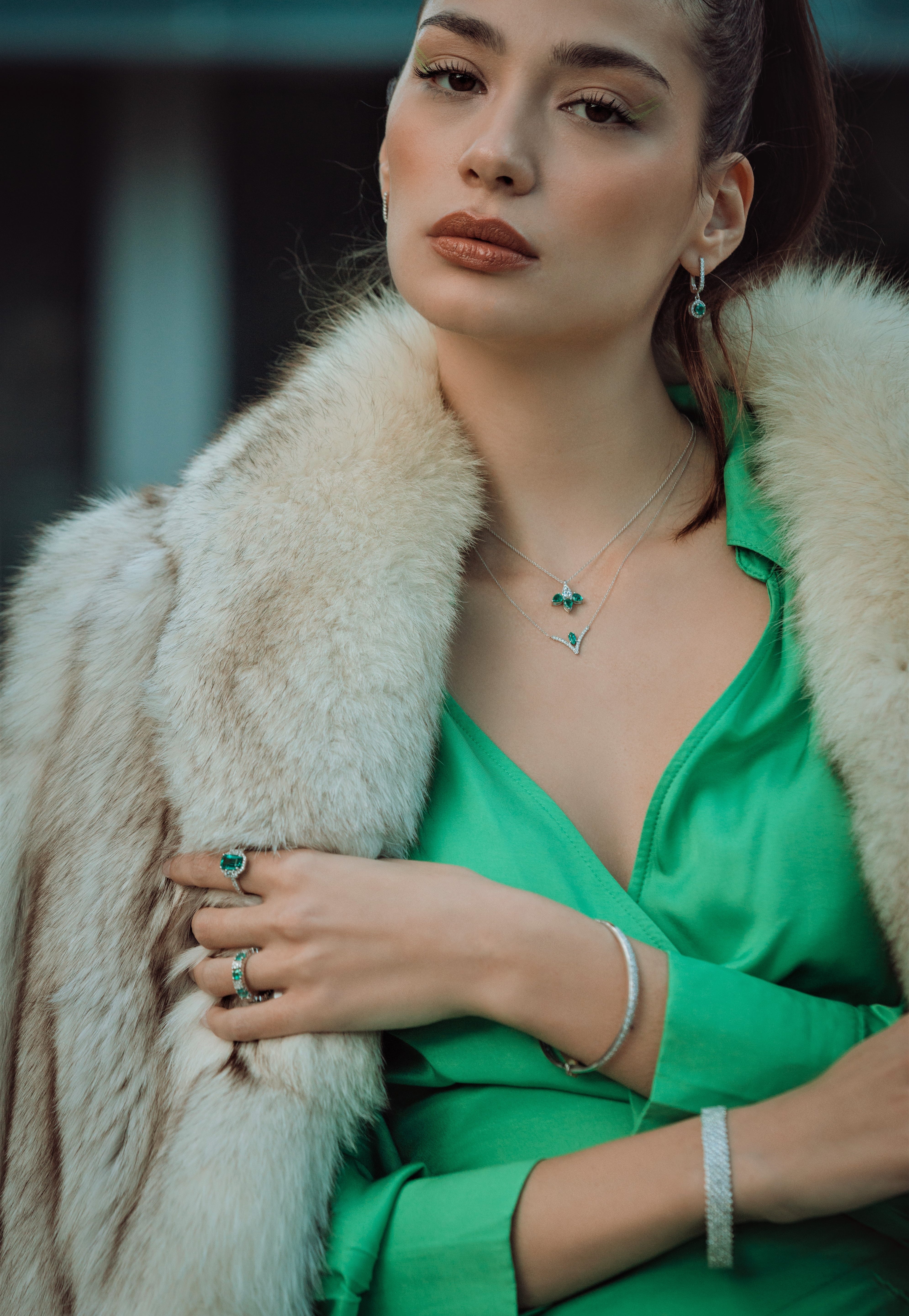 Woman wearing a green dress with a fur coat and jewelry