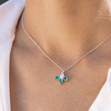 Necklace with a pendant featuring green gemstones worn by a person.
