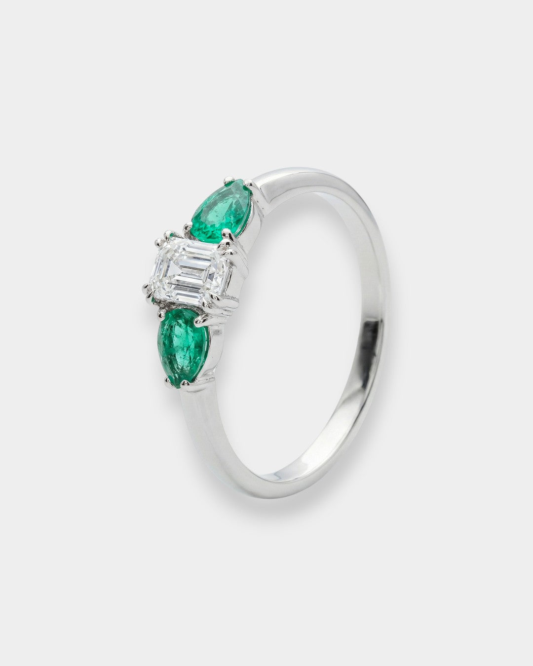 White gold ring with emeralds and diamonds on a white background