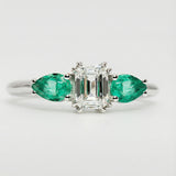 Ring with emerald and diamond design on a light gray background