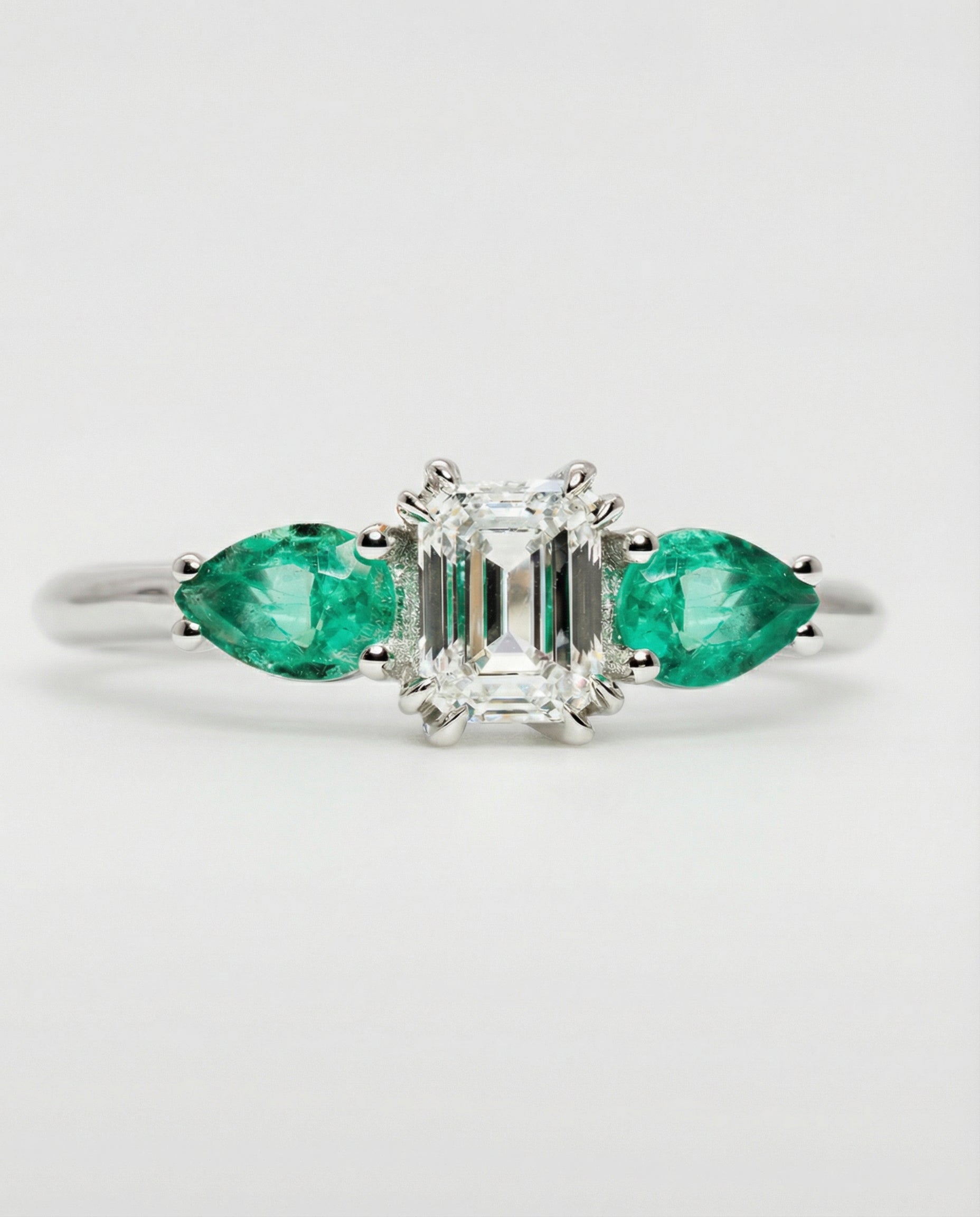 Ring with emerald and diamond design on a light gray background