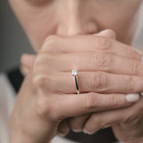 Close-up of a woman's hand with a diamond ring, blurred background