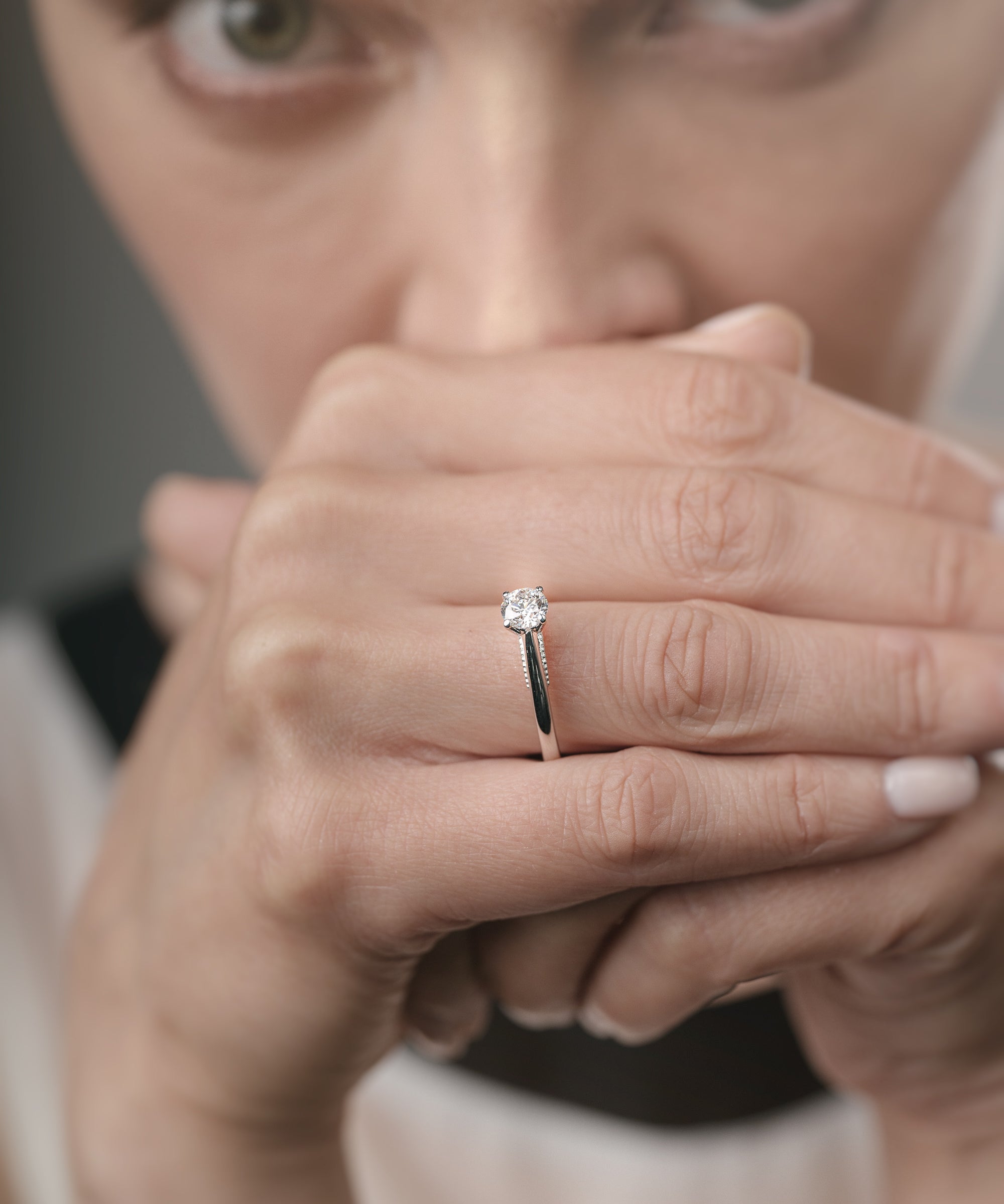 Close-up of a woman's hand with a diamond ring, blurred background