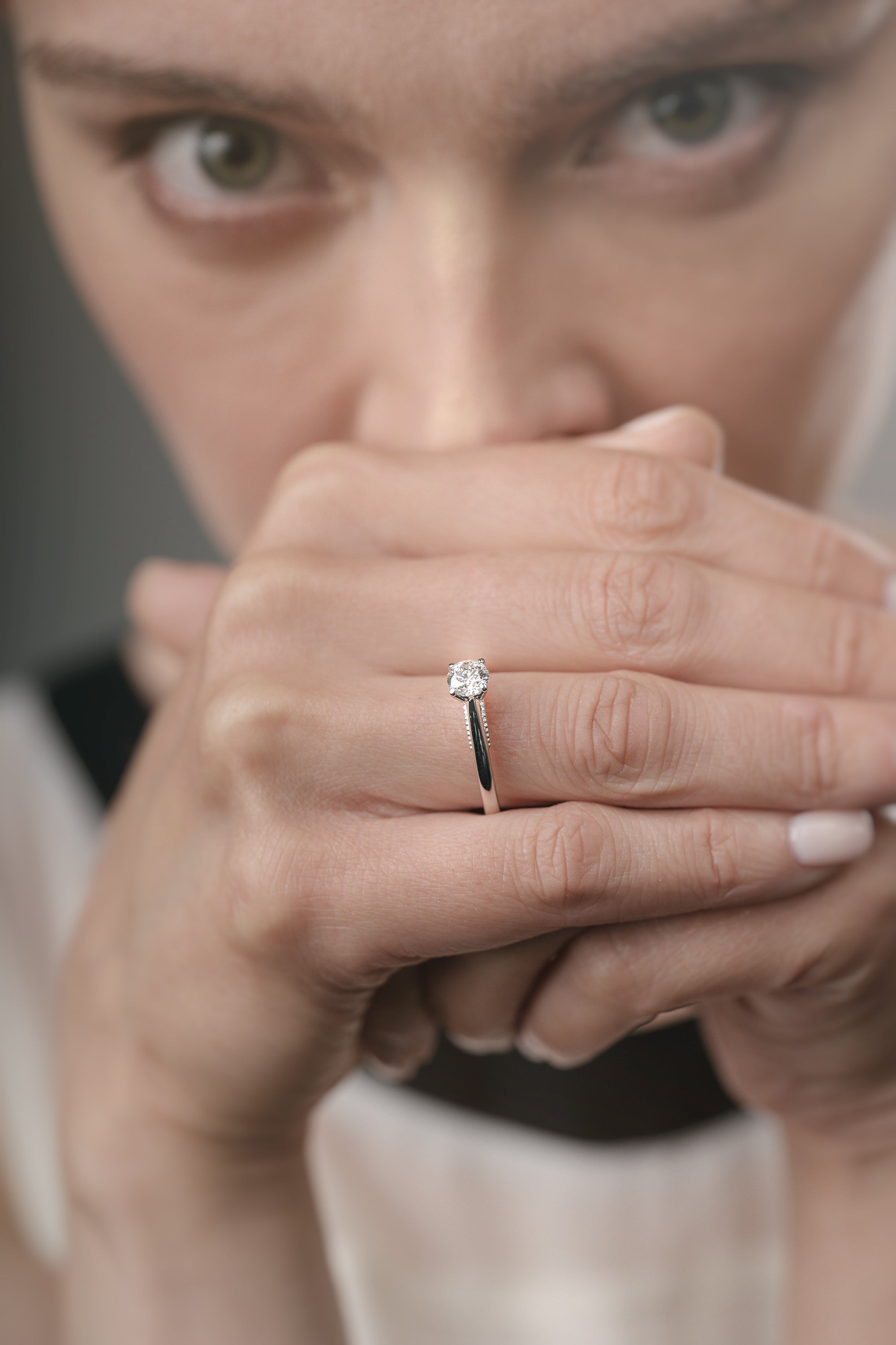 Close-up of a woman's hand with a diamond ring, blurred background