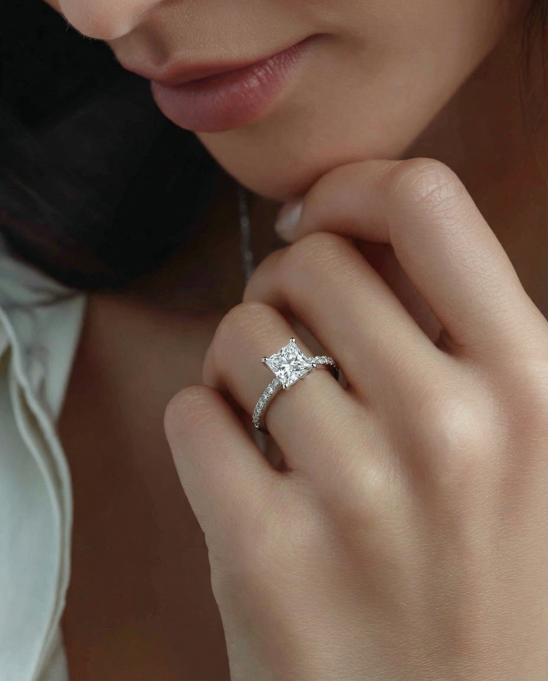 Close-up of a hand wearing a diamond ring with a soft focus background