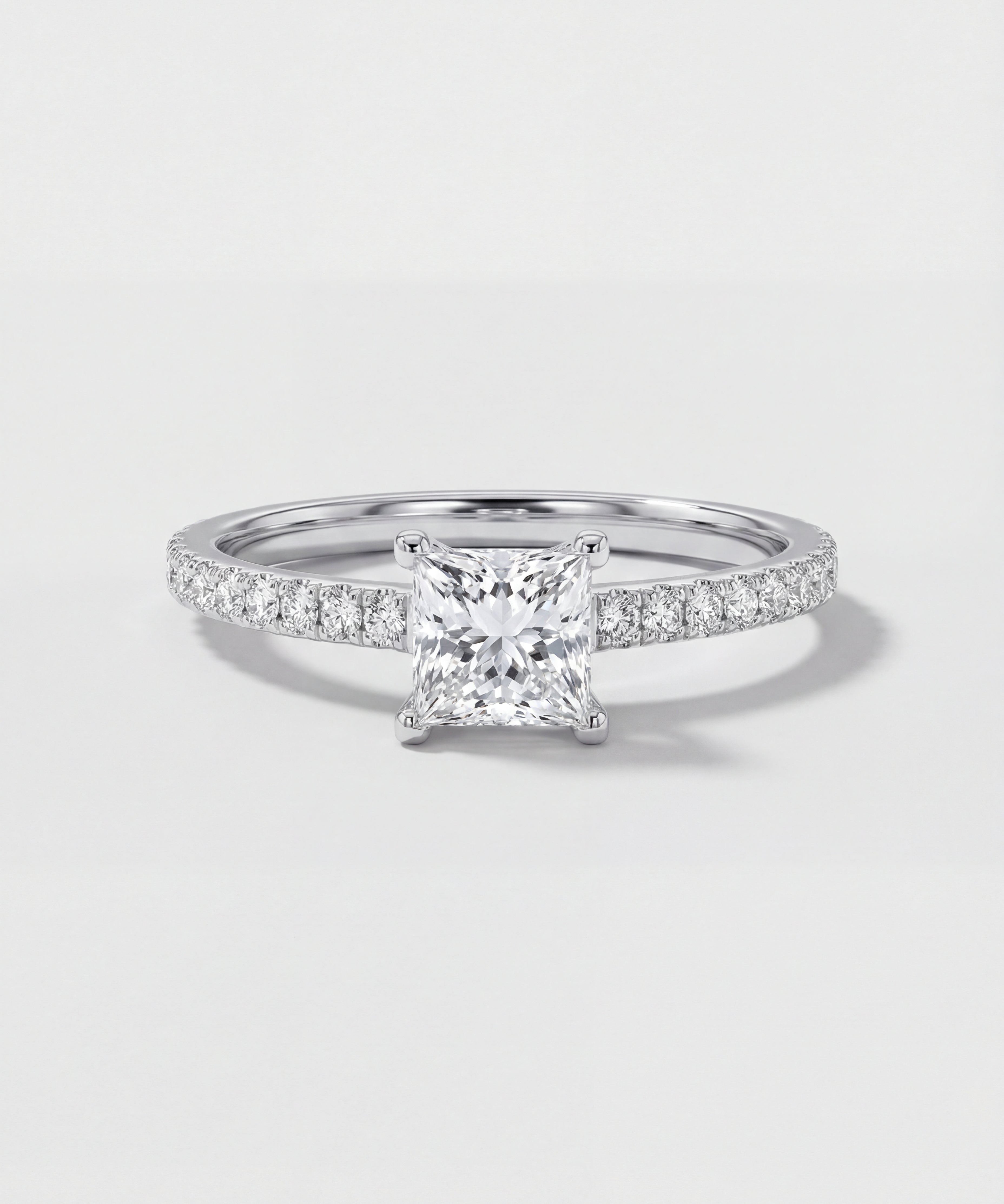 Diamond ring with a square-cut center stone on a light gray background