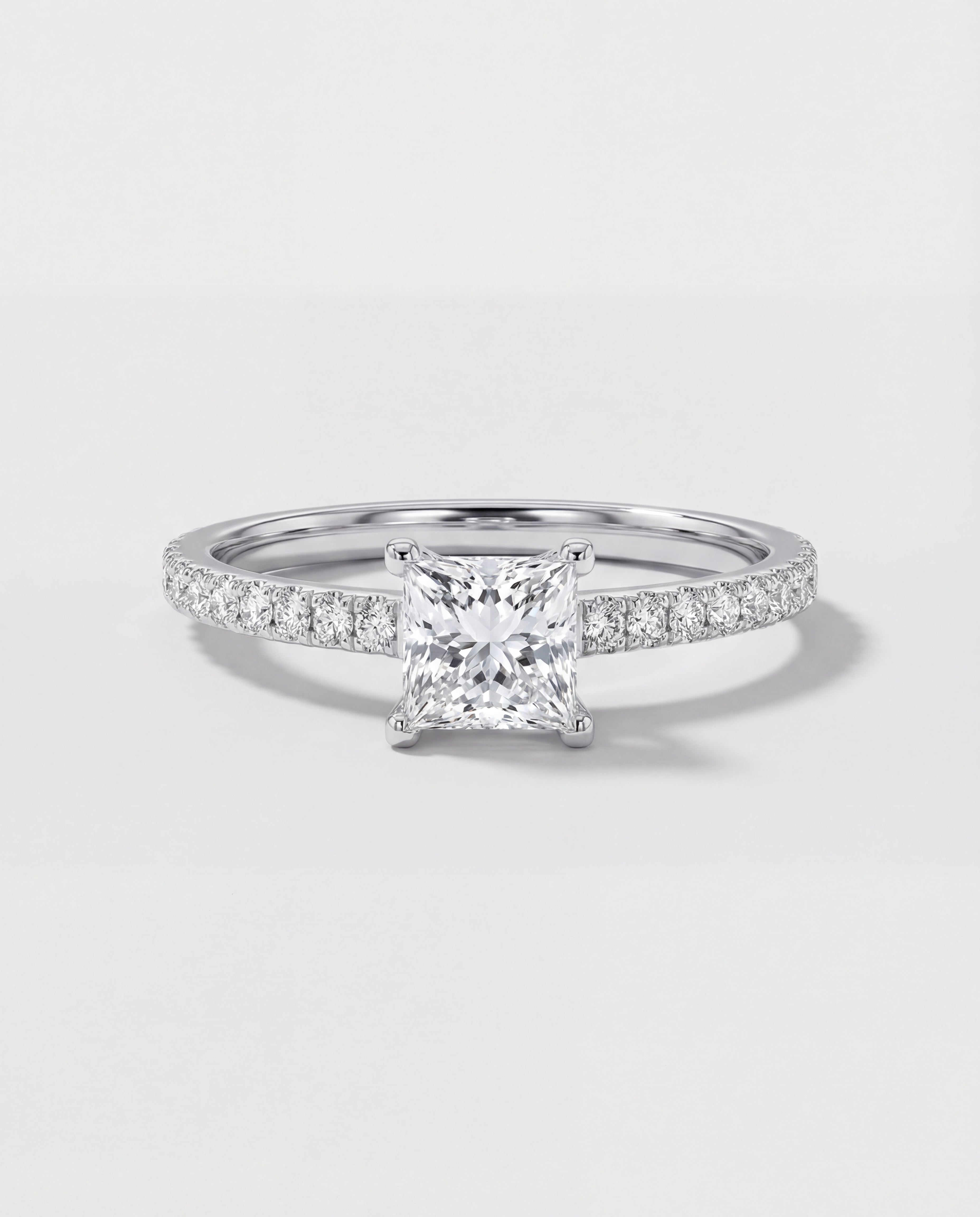 Diamond ring with a square-cut center stone on a light gray background