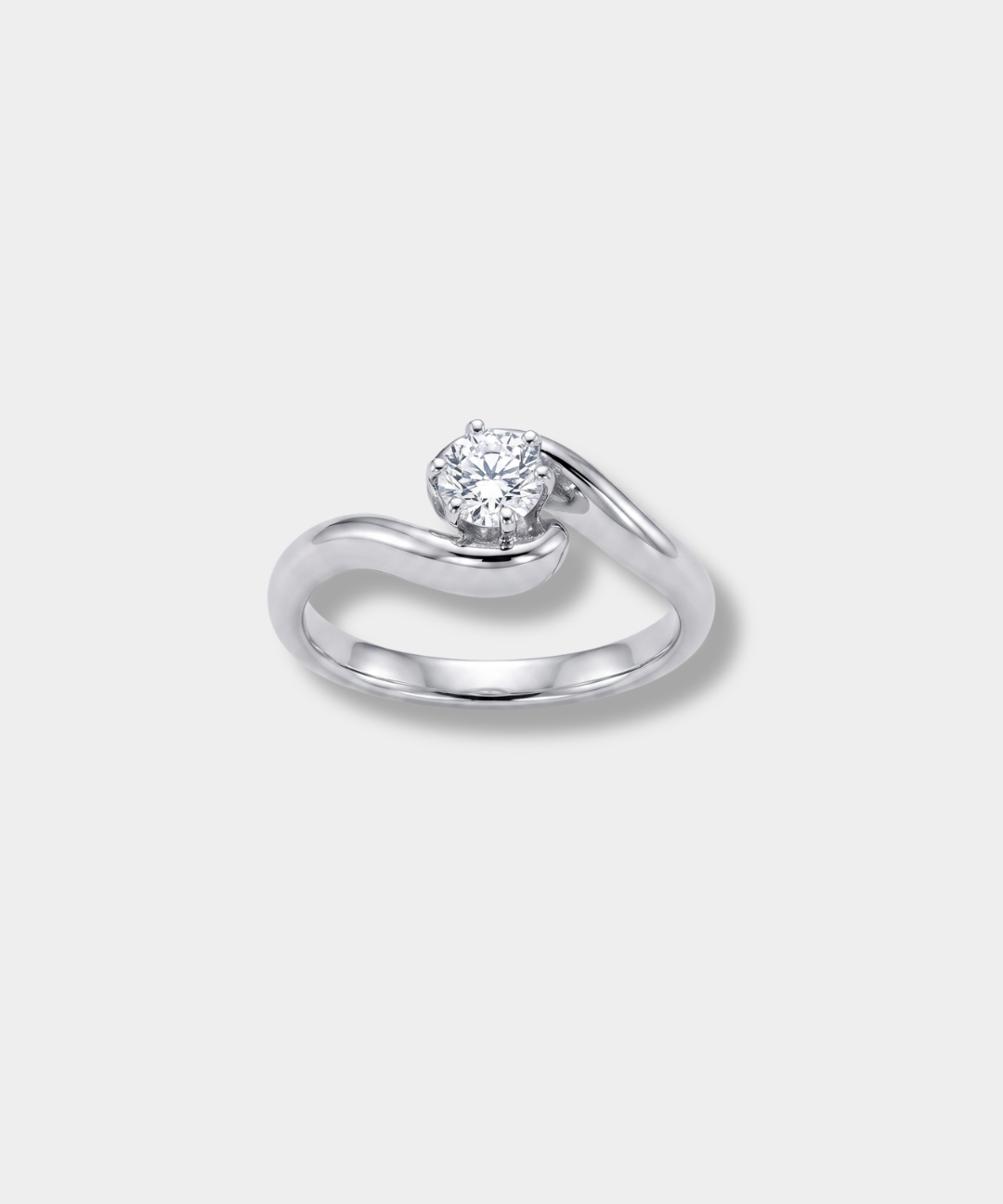 A white-gold engagement ring featuring a round-cut clear gemstone in a curved, flowing band setting, shown on a light gray background.