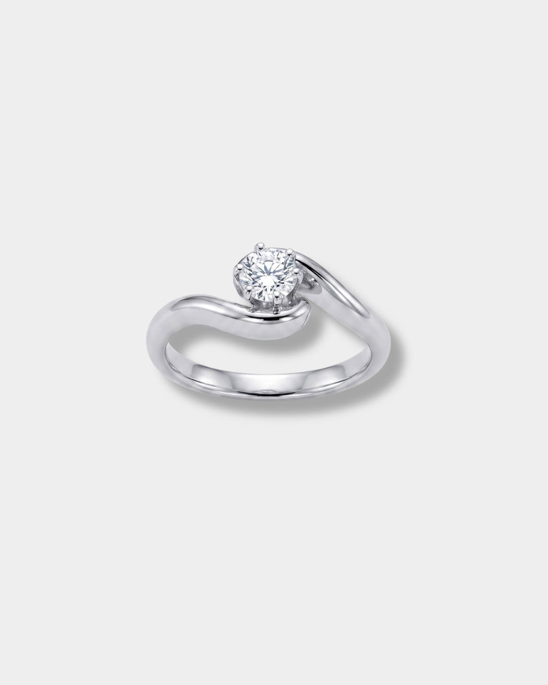 A white-gold engagement ring featuring a round-cut clear gemstone in a curved, flowing band setting, shown on a light gray background.