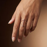 Hand wearing a geometric ring on a dark background
