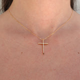 Gold cross necklace on a person's neck