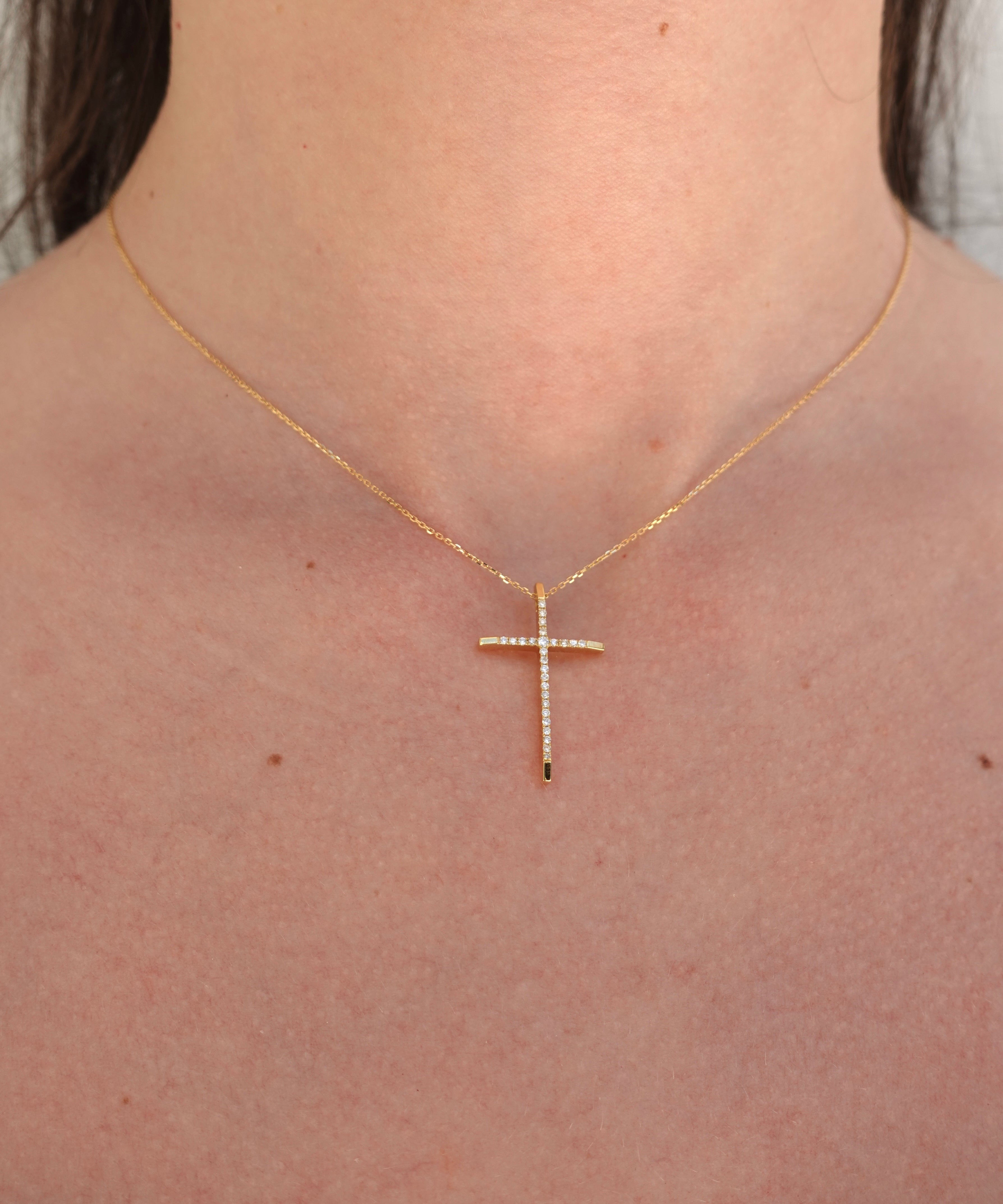 Gold cross necklace on a person's neck