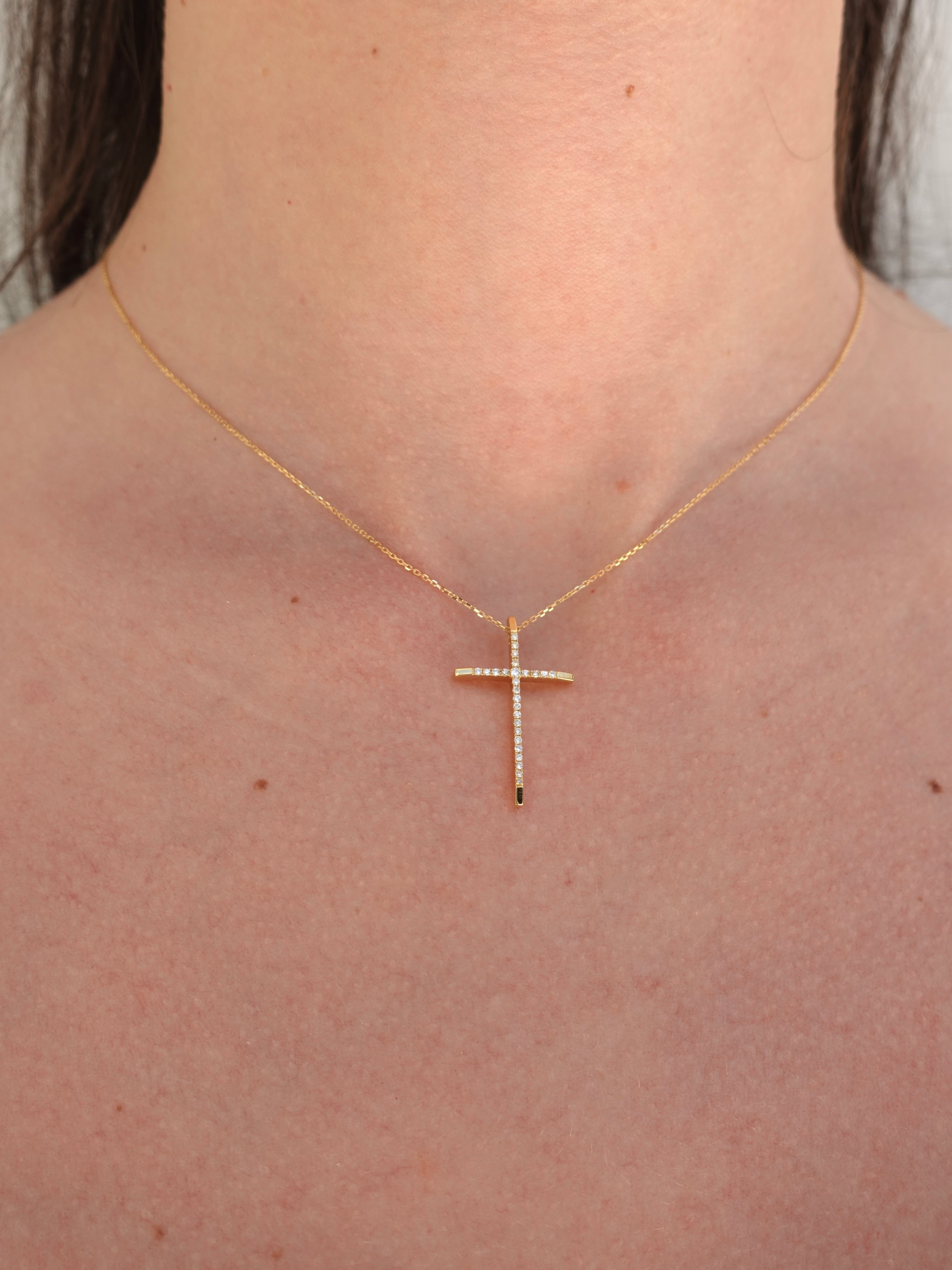 Gold cross necklace on a person's neck