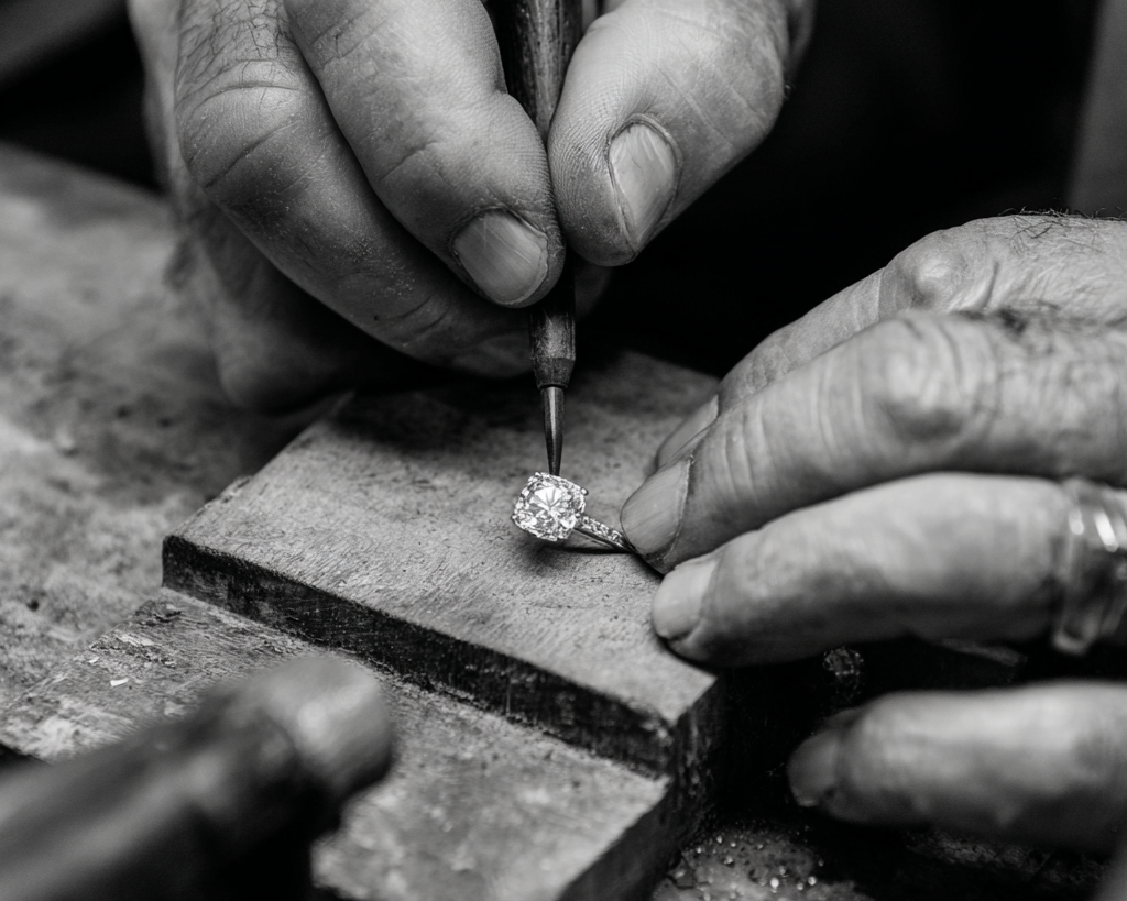 Jeweler working on a diamond with tools in a workshop setting
