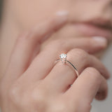 Close-up of a hand wearing a diamond ring with a blurred background