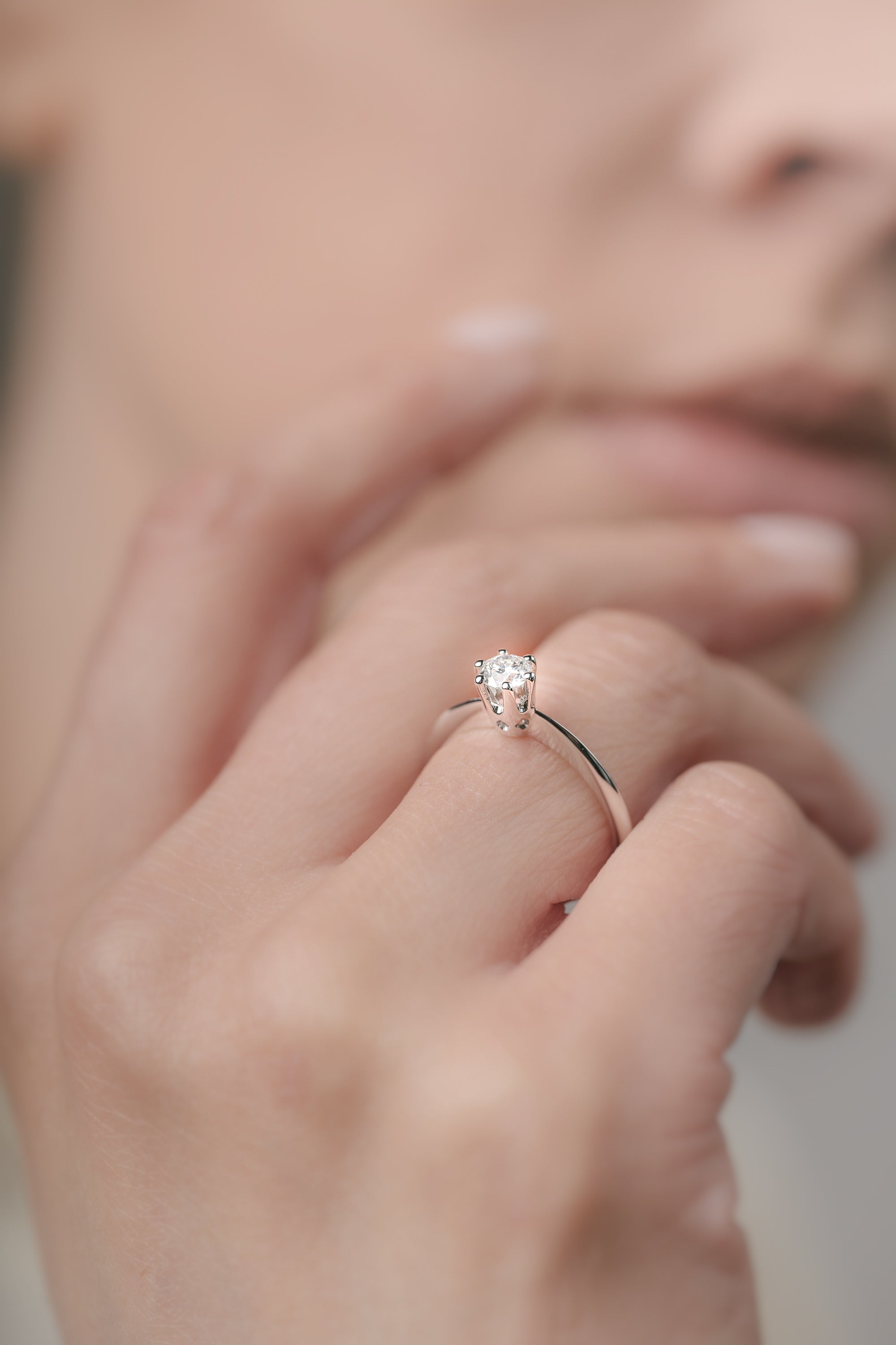 Close-up of a hand wearing a diamond ring with a blurred background