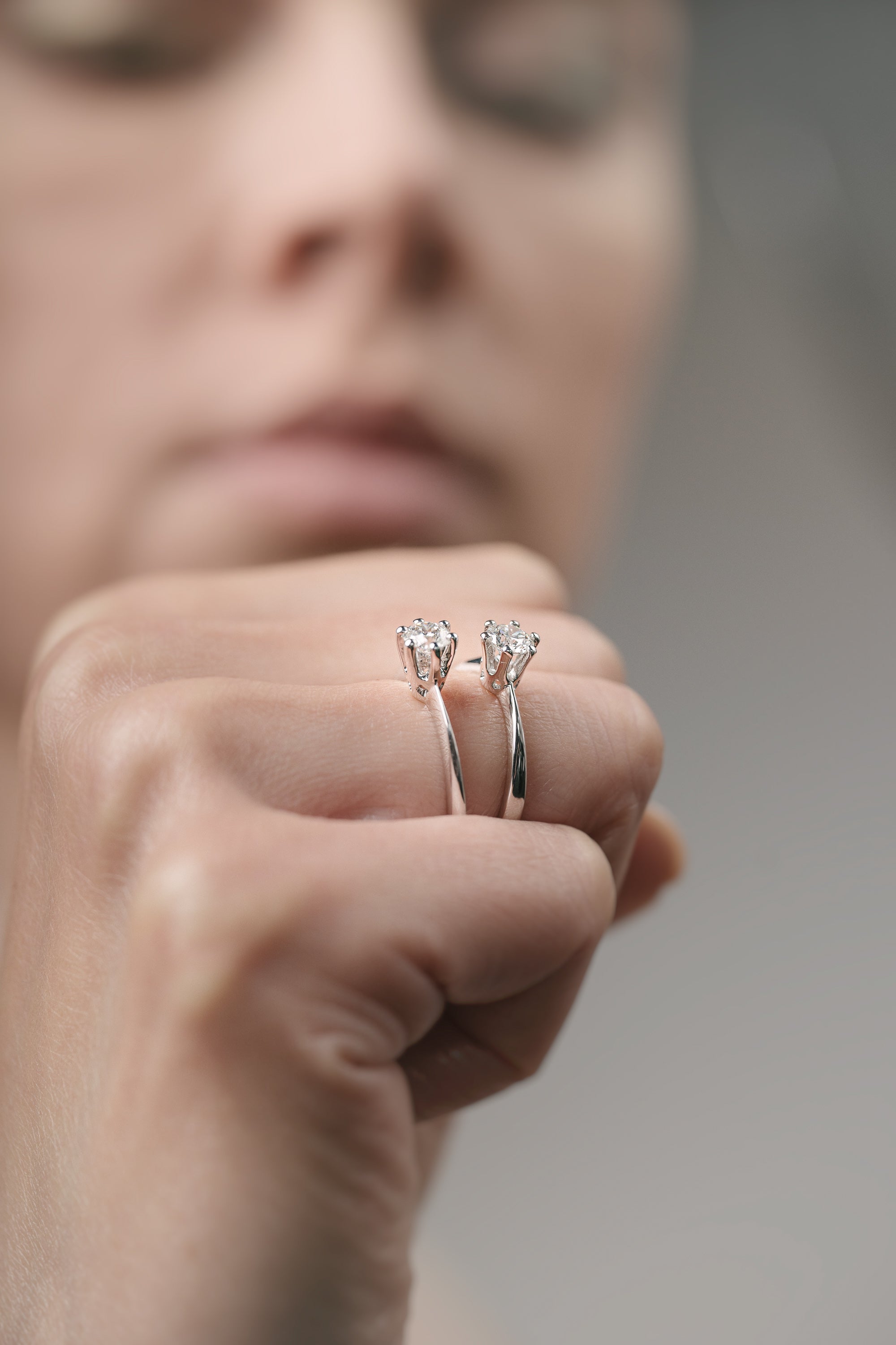 Close-up of a hand holding two diamond earrings against a blurred background