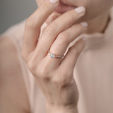 Close-up of a hand wearing a diamond ring with a blurred background
