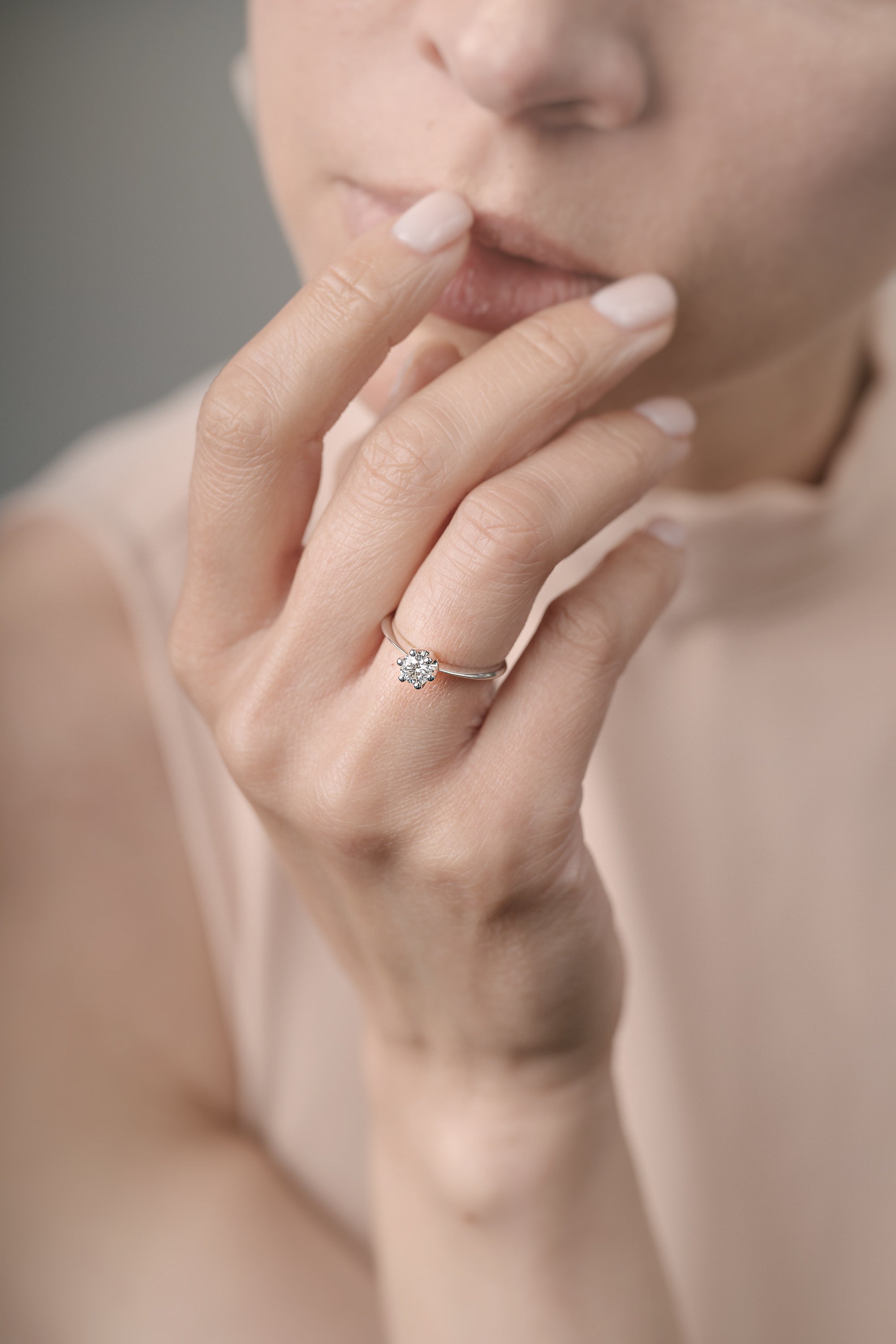 Close-up of a hand wearing a diamond ring with a blurred background