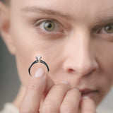 Close-up of a person holding a diamond ring near their face.