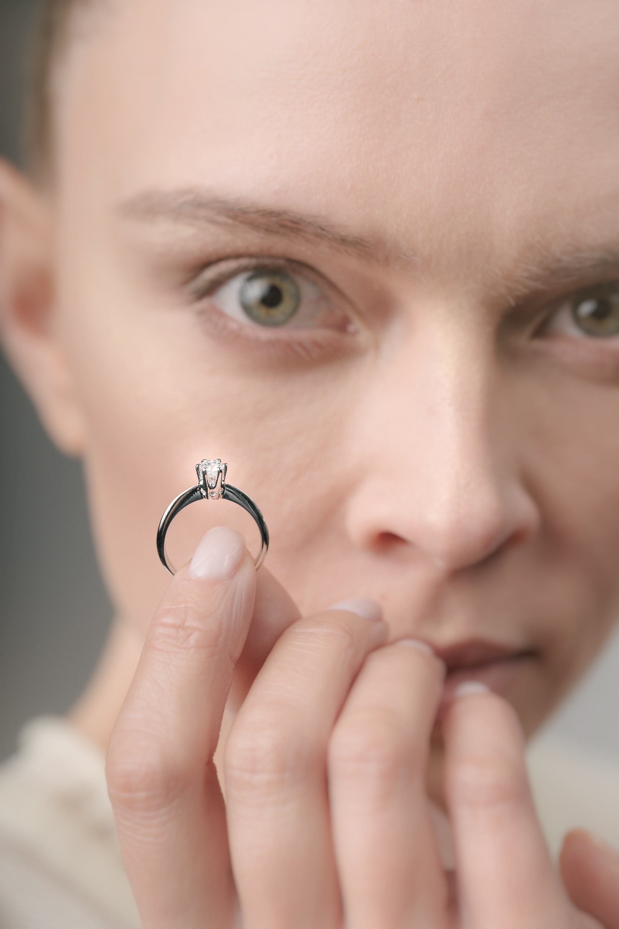 Close-up of a person holding a diamond ring near their face.