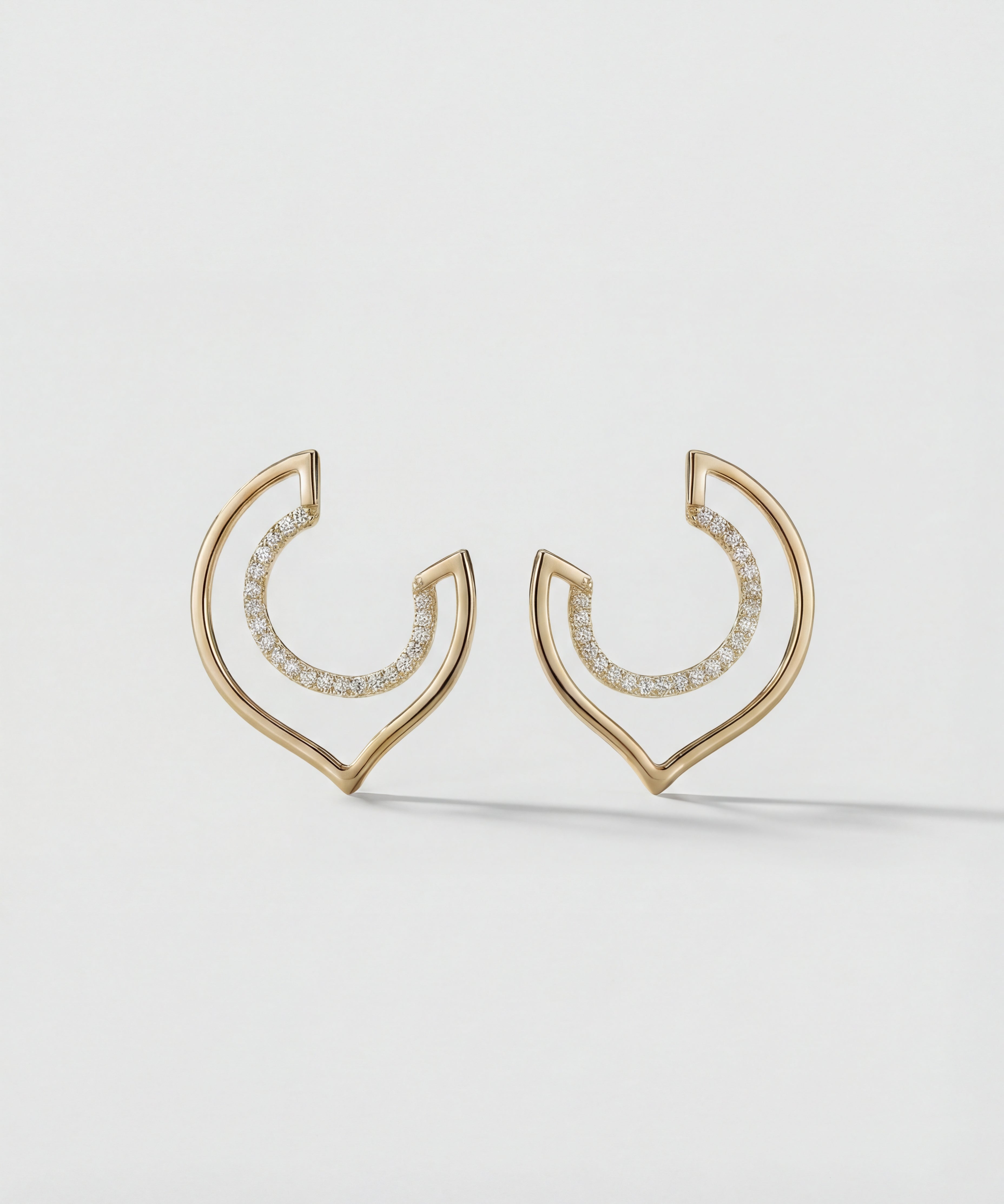 Gold hoop earrings with embedded stones on a light gray background