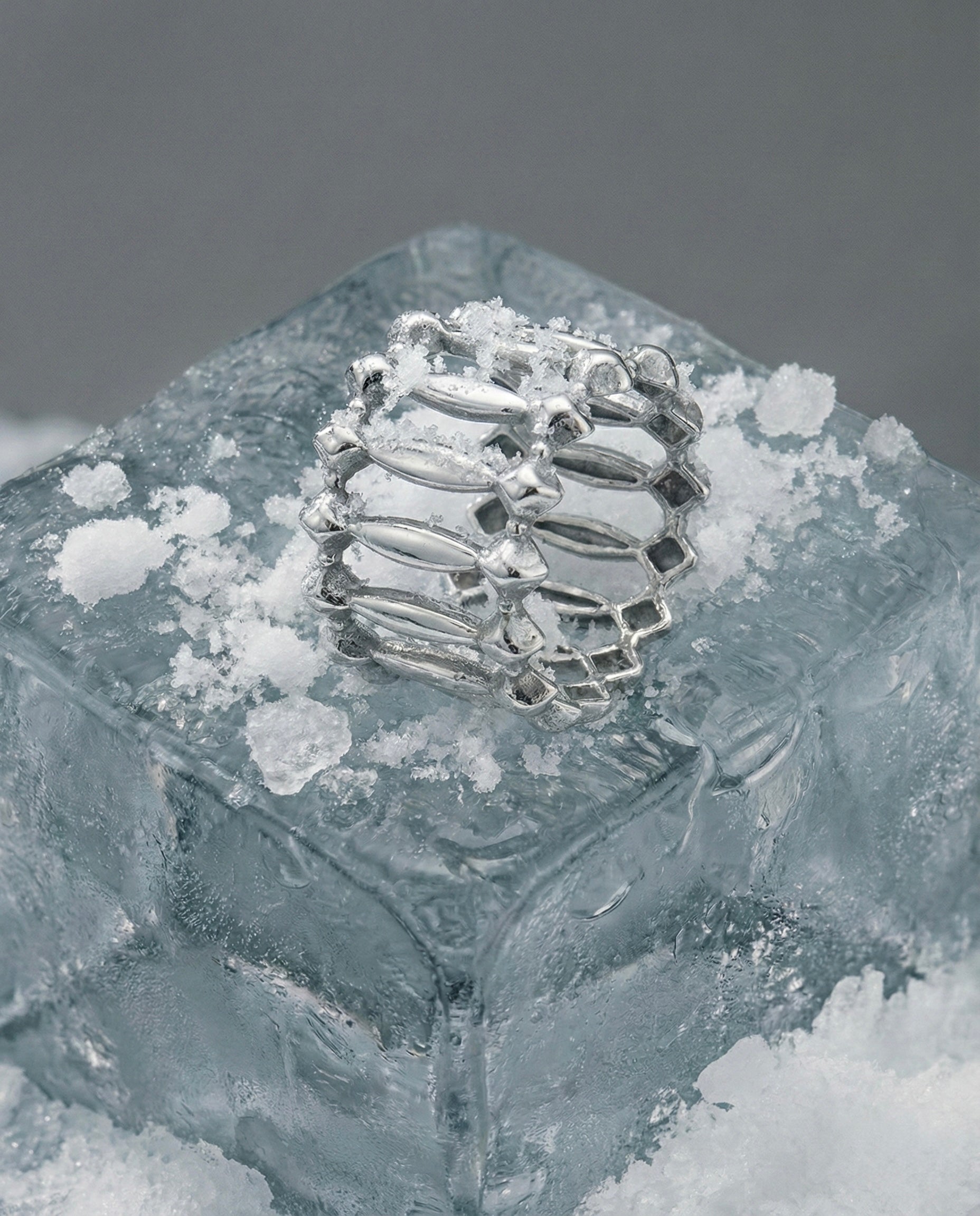 White gold ring on a block of ice with a gray background