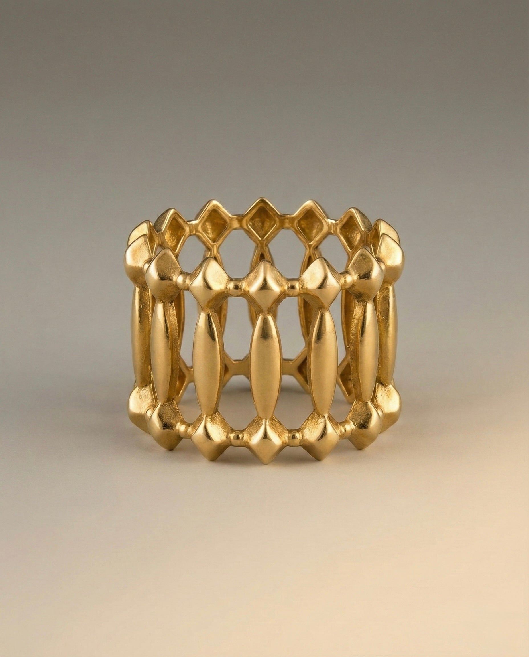 Gold ring with geometric design on a beige background
