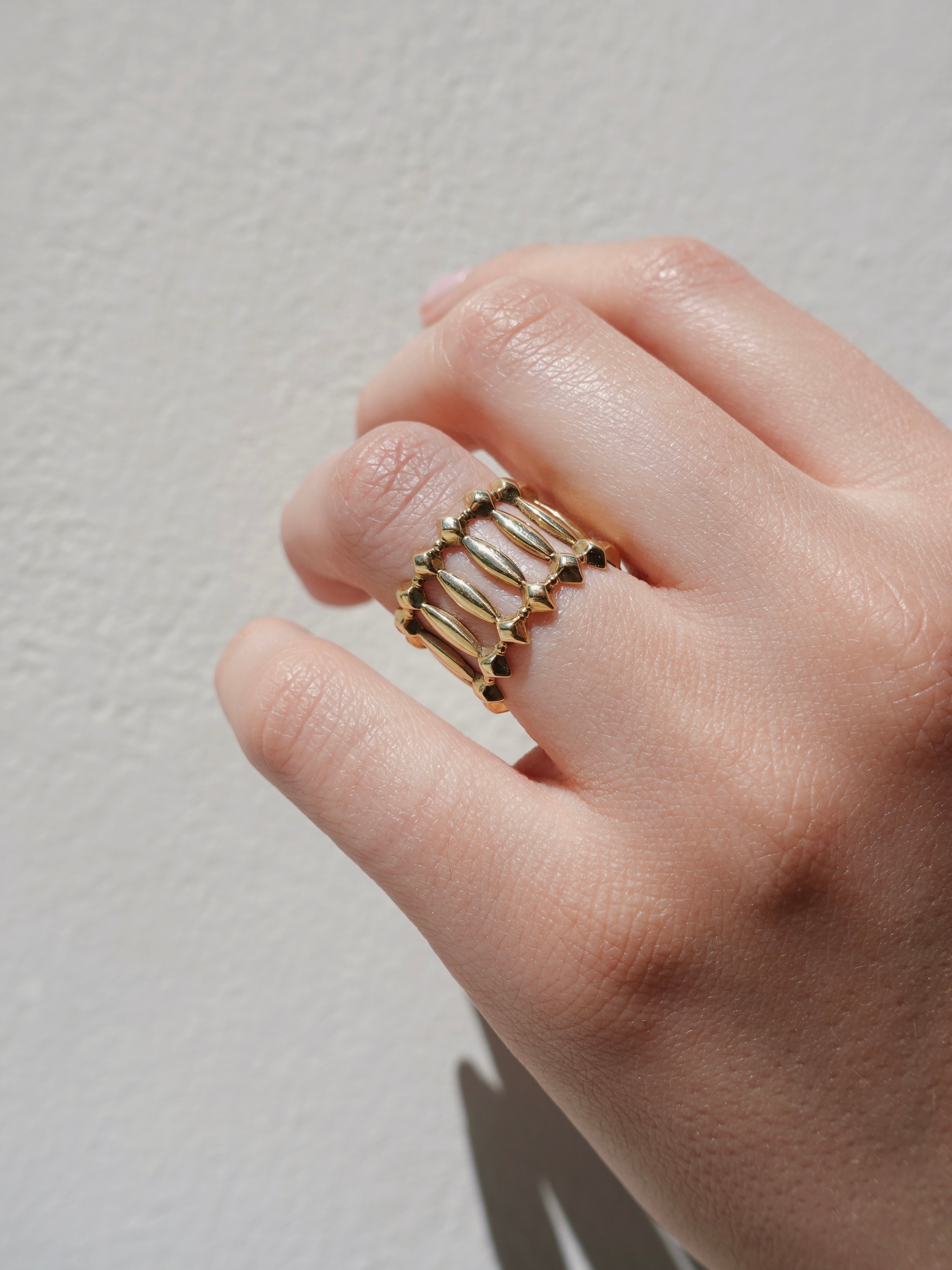 Gold ring with architectural structure on a neutral background